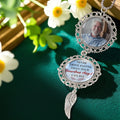 Custom memorial photo ornament with angel wing charm displayed in floral setting