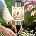 Hand placing a memorial solar garden light with grandpa photo among flowers