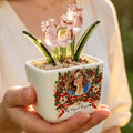 Hand holding personalized pink glass tulip pot with Christmas wreath design