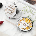 Silver personalized compact mirror with yellow flower wreath and quote on marble