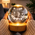 Hands cradling glowing papel picado memorial globe lamp with name and years