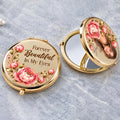 Gold compact mirror open on gray stone showing photo portrait framed by peonies