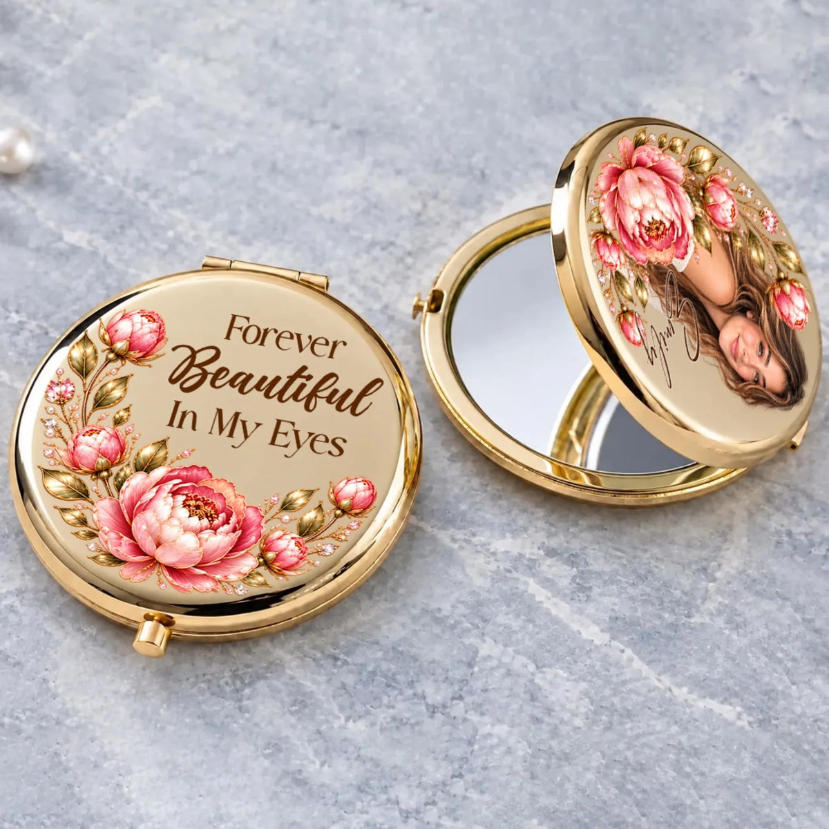 Gold compact mirror open on gray stone showing photo portrait framed by peonies
