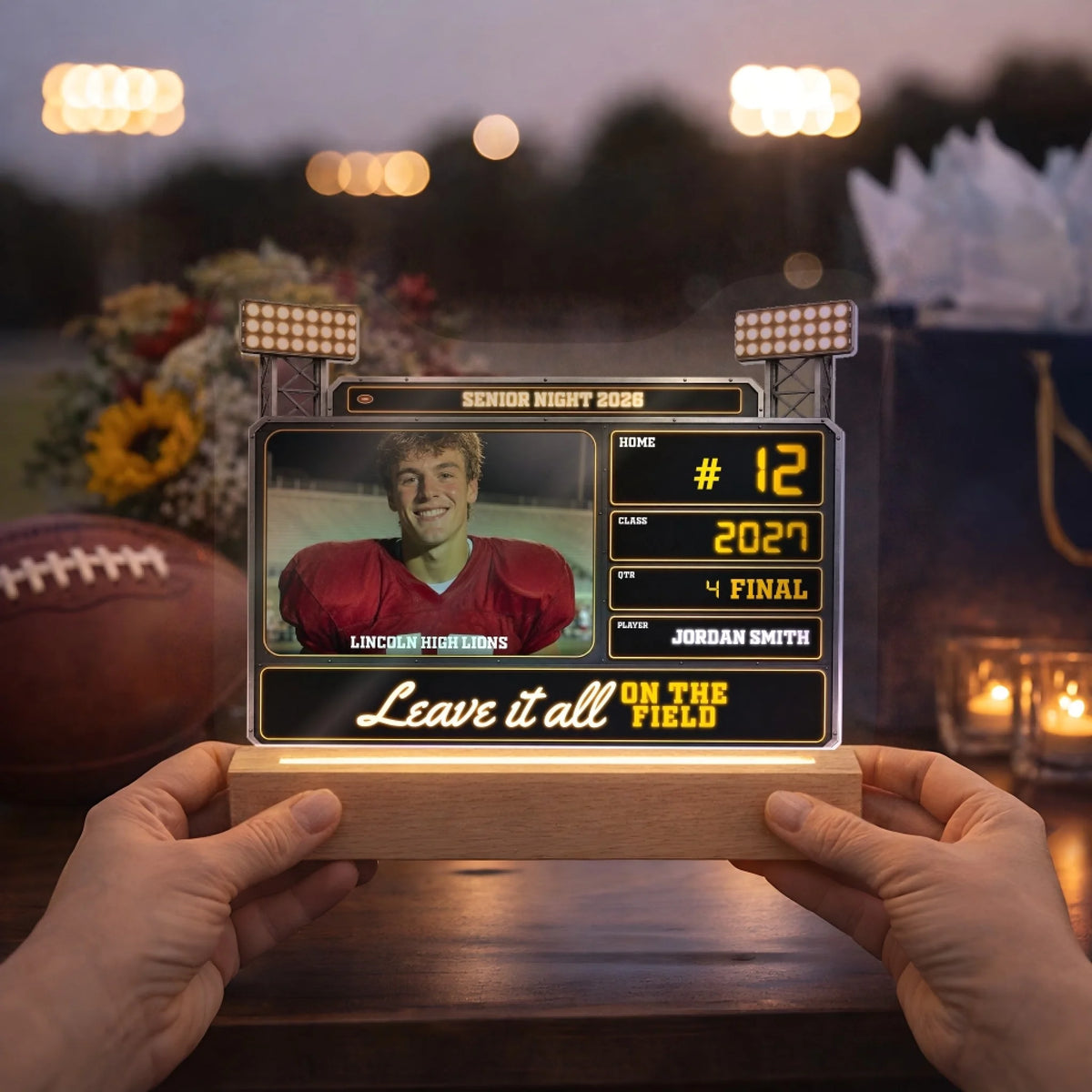 Hands holding a personalized Senior Night photo lamp at an outdoor party