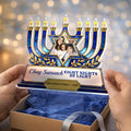 Hands lifting personalized Hanukkah menorah plaque from a gift box