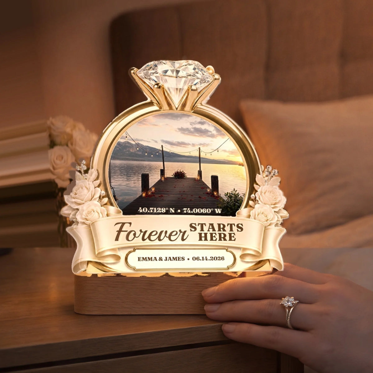 Glowing engagement night light on a bedside table beside a hand with ring