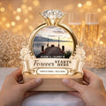 Hands holding a personalized engagement photo night light with champagne glasses behind