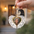 Hand holding a memorial angel wings photo keychain with car keys