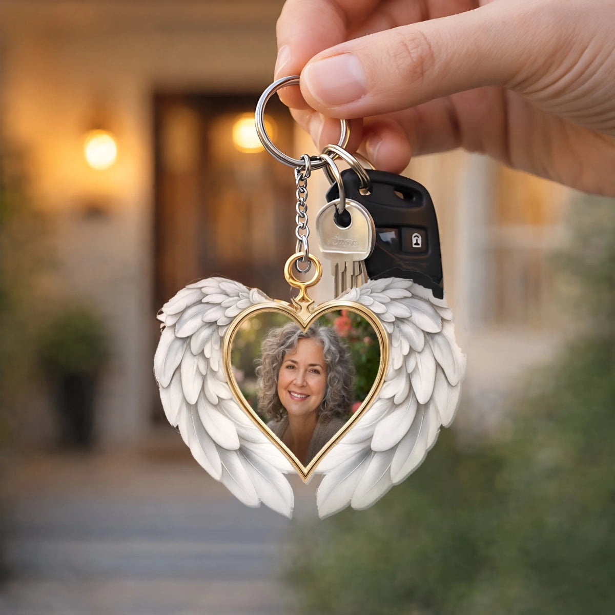 Hand holding a memorial angel wings photo keychain with car keys