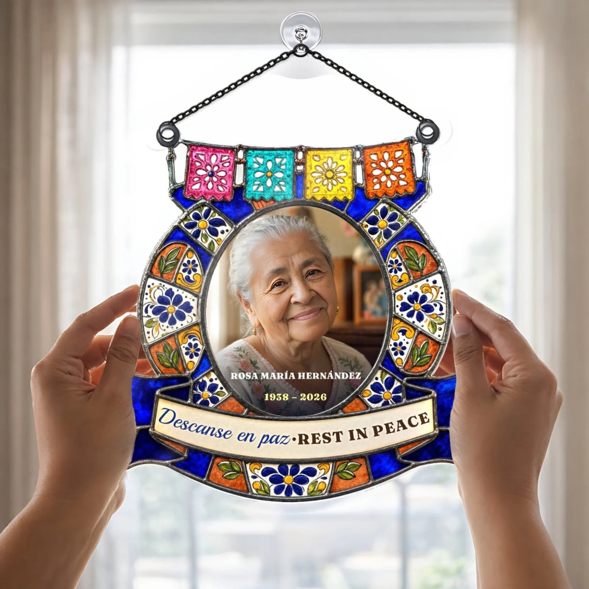 Hands holding a bilingual Descanse en paz memorial suncatcher