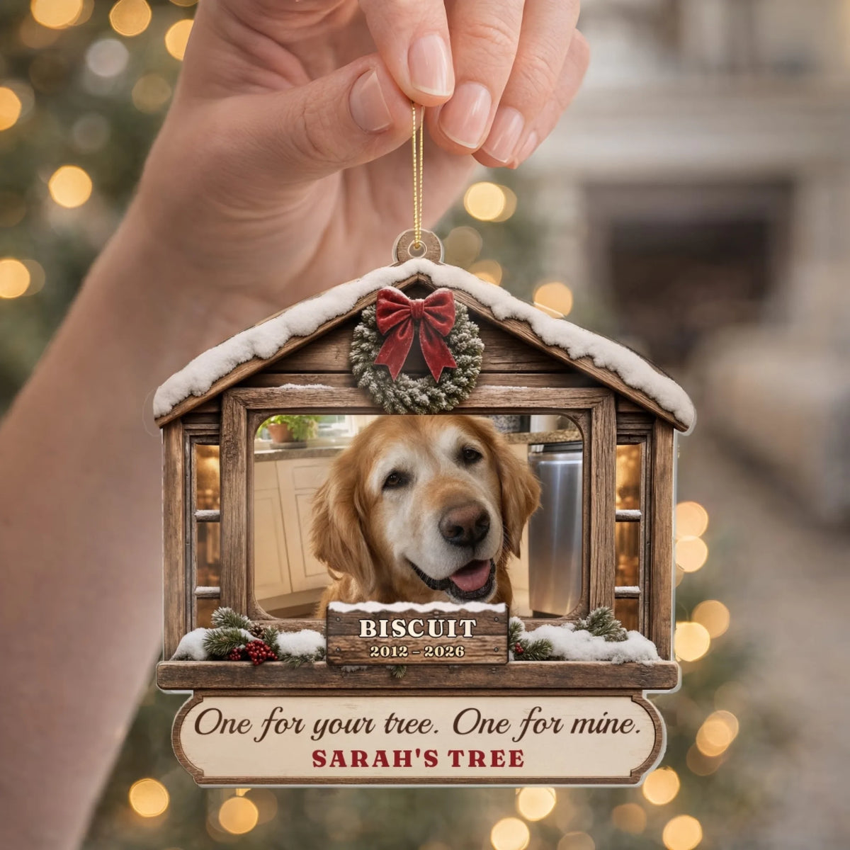 Hand holding a snowy cabin pet memorial ornament with tree name