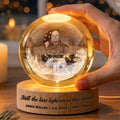 Hand holding a glowing veteran memorial globe lamp with engraved base