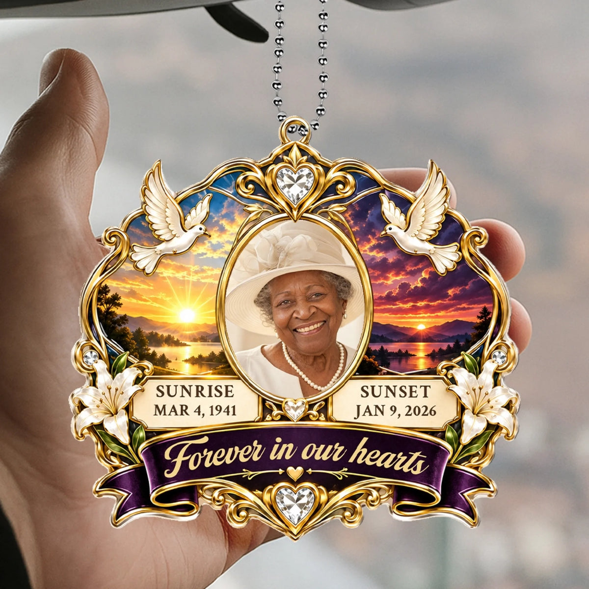 Hand holding a sunrise sunset memorial car hanger with doves and lilies