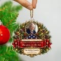 Fingers hanging the personalized veteran ornament by its rope beside a red Christmas bauble