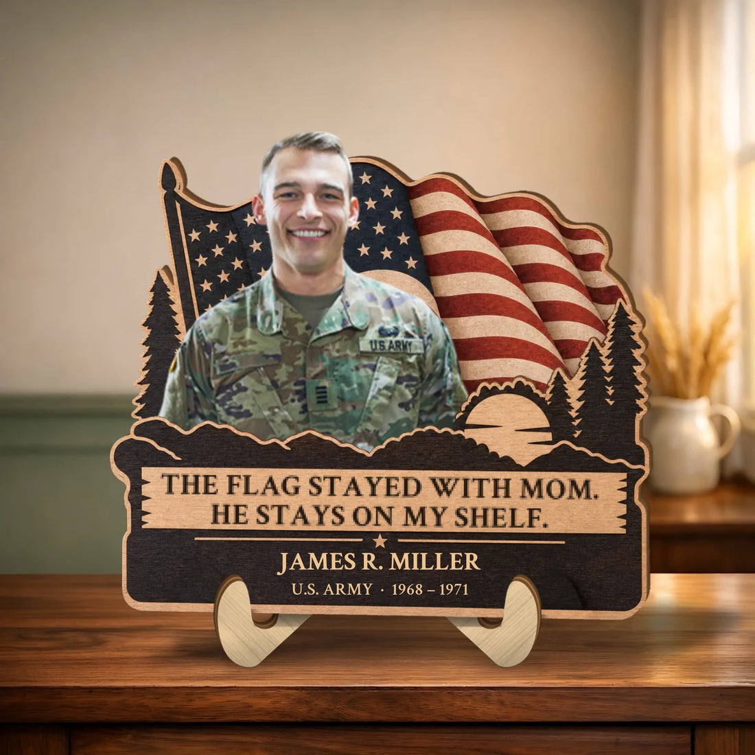 Personalized veteran memorial wooden plaque with photo, waving flag and pines on a table