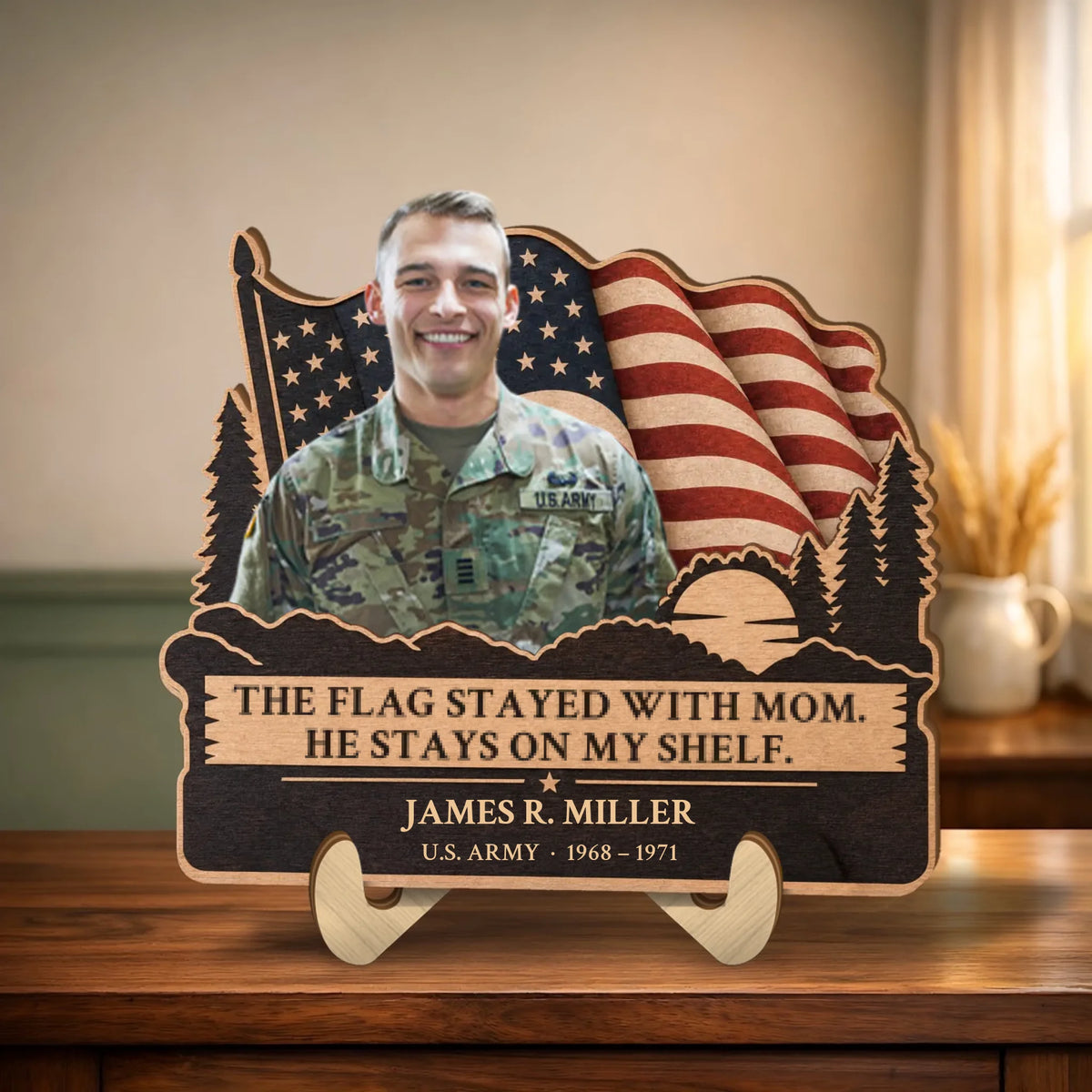 Personalized veteran memorial wooden plaque with photo, waving flag and pines on a table