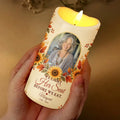 Hand holding glowing We Light Her Seat memorial candle with photo