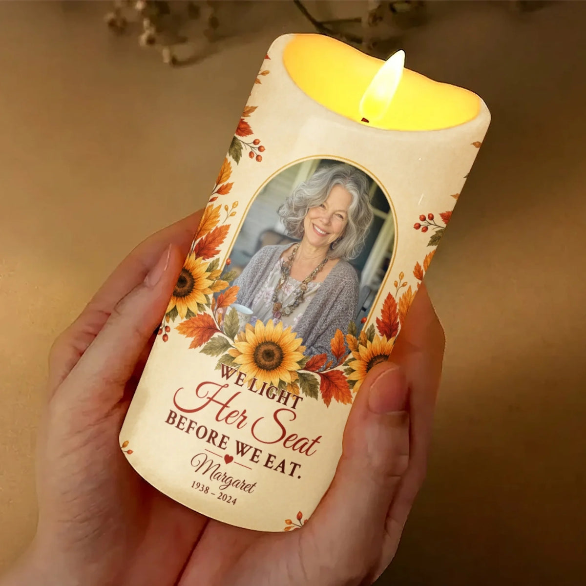 Hand holding glowing We Light Her Seat memorial candle with photo