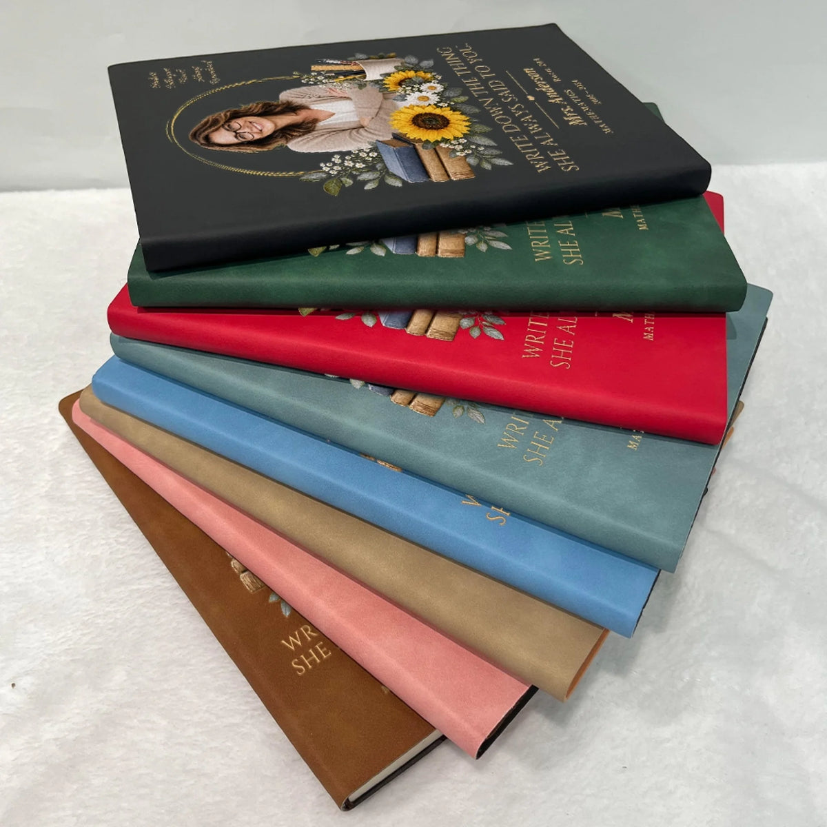 Stack of teacher memorial leather journals in eight cover colors