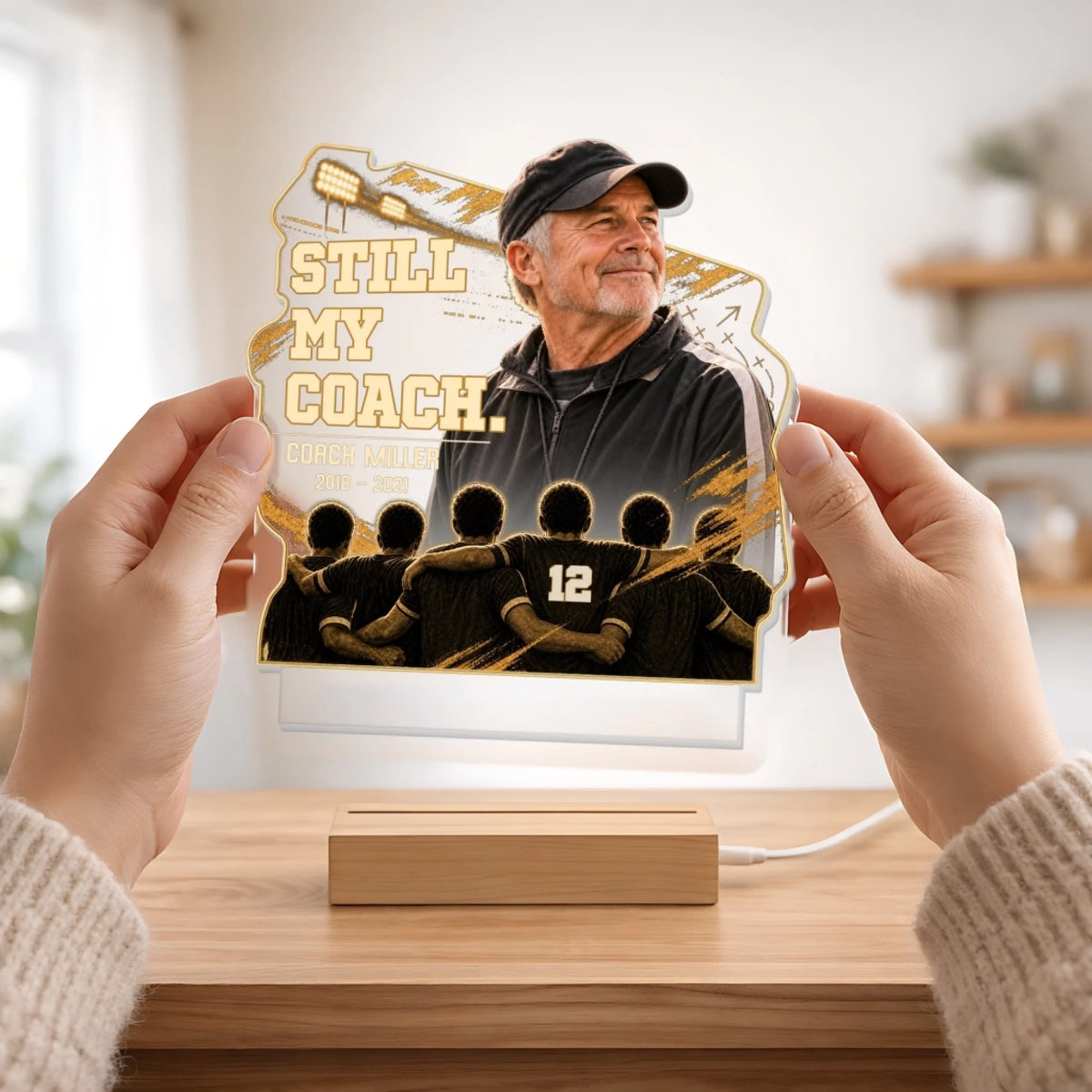 Hands holding acrylic coach memorial plaque above its wooden base