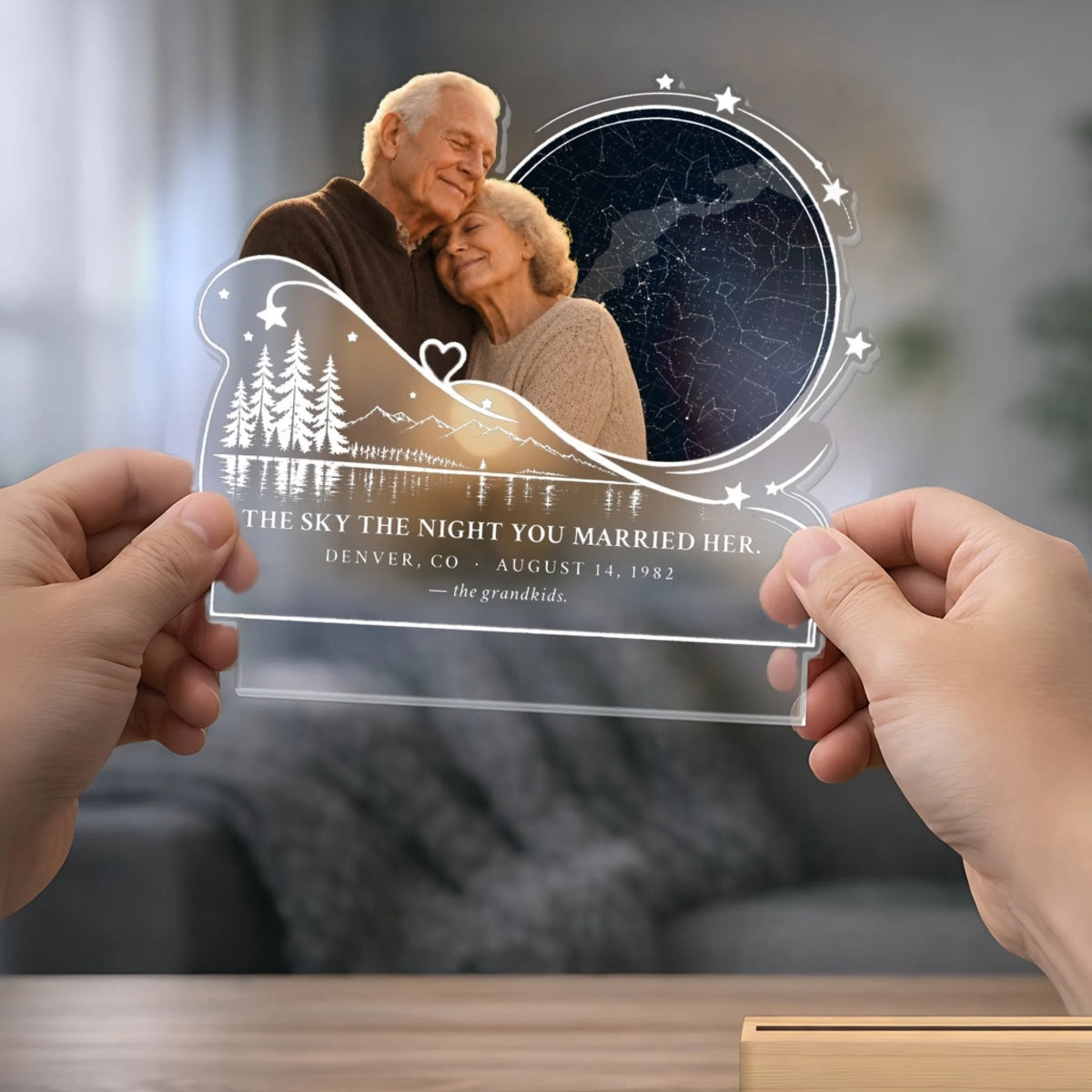 Hands holding clear acrylic star map panel above its wooden base
