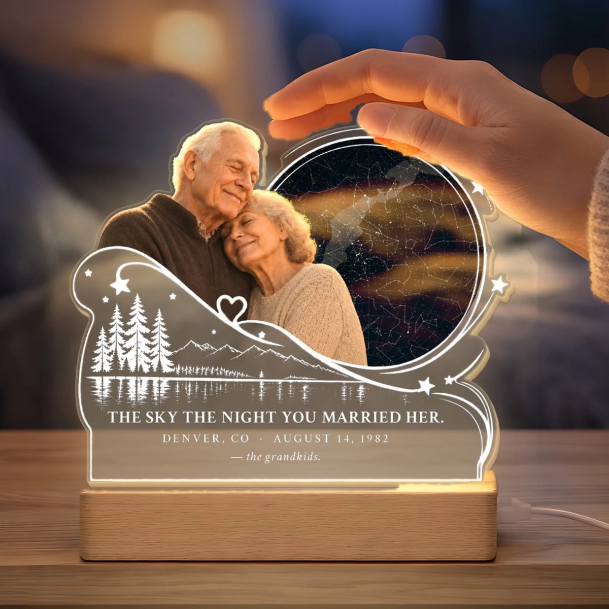 Hand above glowing memorial star map night light with wedding date
