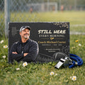 Personalized coach memorial stone on grass beside a whistle near a sports field